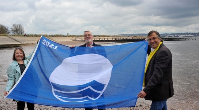 Cllr Linda Goodman-Bradbury, Cllr Andrew MacGregor and Cllr Martin Wrigley hold up the Blue Flag at Dawlish Warren beach Cllr Linda Goodman-Bradbury, Cllr Andrew MacGregor and Cllr Martin Wrigley hold up the Blue Flag at Dawlish Warren beach